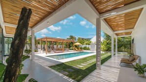 A modern outdoor pool area with a wooden pergola, lounge chairs, and a well-maintained lawn. - Villa Air - 2BR Villa in Pererenan (Canggu)
