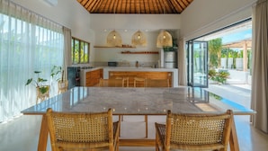 A modern kitchen with a marble countertop, wooden ceiling, and large windows. - Villa Air - 2BR Villa in Pererenan (Canggu)