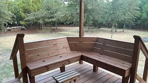 A wooden bench with a small table in a covered outdoor area. - PineyWoods House Forest Retreat (Bastrop County)