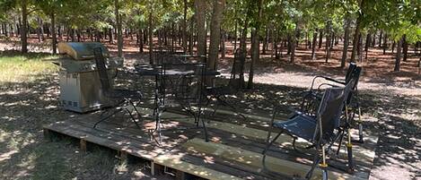 An outdoor seating area with metal chairs and a grill.