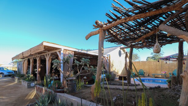 Ein überdachter Außenbereich mit einer Holz-Pergola, einem Pool und verschiedenen Pflanzen.