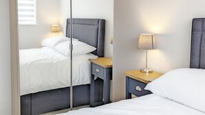 A modern hotel room with a bed, bedside tables, and a mirror.