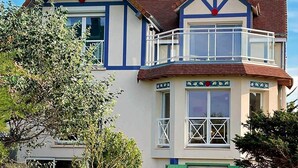 A two-story house with a balcony, a chimney, and a small garden area. - Entire Seaside House, 160m² – 3 Bedrooms, Sleeps 6 (Ouistreham)