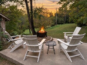 Een terras met Adirondack-stoelen en een vuurkorf.
