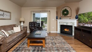 A living room with a fireplace, a sofa, a coffee table, and a television. - On River/Mt. LeConte Views/DwTn (Pigeon Forge)