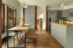 Une cuisine moderne avec une table à manger en bois, un banc et des luminaires suspendus.