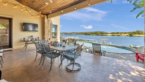 An outdoor patio with a pool, a table with chairs, a ceiling fan, and a TV mounted on the wall. - 119 Christopher | Concierge Services Available (Kingsland)