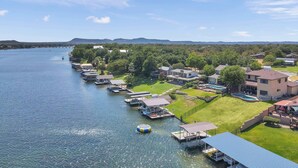 A lakeside property with docked boats, a swimming pool, and a bridge in the background. - 119 Christopher | Concierge Services Available (Kingsland)