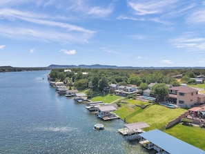 Une propriété au bord du lac, avec des bateaux amarrés, une piscine et un pont en arrière-plan.