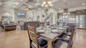 A spacious living area with a fireplace, a dining table set for six, and a kitchen with stainless steel appliances. - 119 Christopher | Concierge Services Available (Kingsland)