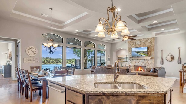 A spacious kitchen with a large island, a dining area with chairs, a fireplace, and a television. - 119 Christopher | Concierge Services Available (Kingsland)