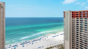 Vista da praia com um hotel imponente ao primeiro plano.