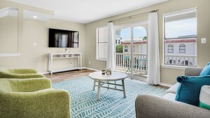A living room with a round table, green chairs, a sofa, and large windows with curtains. - 🌊Fully Renovated | 500ft to Beach | 2 BR | Beach Within Reach🌊 (Miramar Beach)