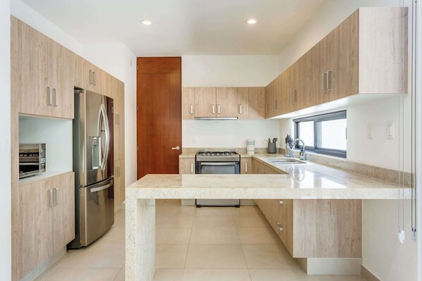A modern kitchen with stainless steel appliances, a central island, and wooden cabinetry.