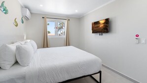 Une chambre à coucher avec un lit, une télévision et une fenêtre avec des rideaux.
