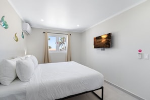 A bedroom with a bed, a television, and a window with curtains. - Rooftop Terrace Views: 2BR Condo w/ Pool (Noord)