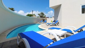 Une piscine avec des chaises longues et un bâtiment en arrière-plan.