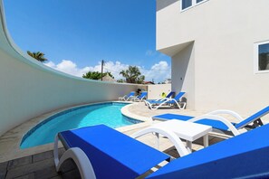 A swimming pool with lounge chairs and a building in the background. - Rooftop Terrace Views: 2BR Condo w/ Pool (Noord)