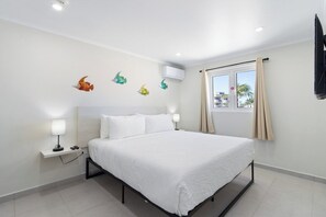 Ein Hotelzimmer mit Bett, Nachttischlampen, einem Fenster mit Vorhängen und Wanddekorationen.