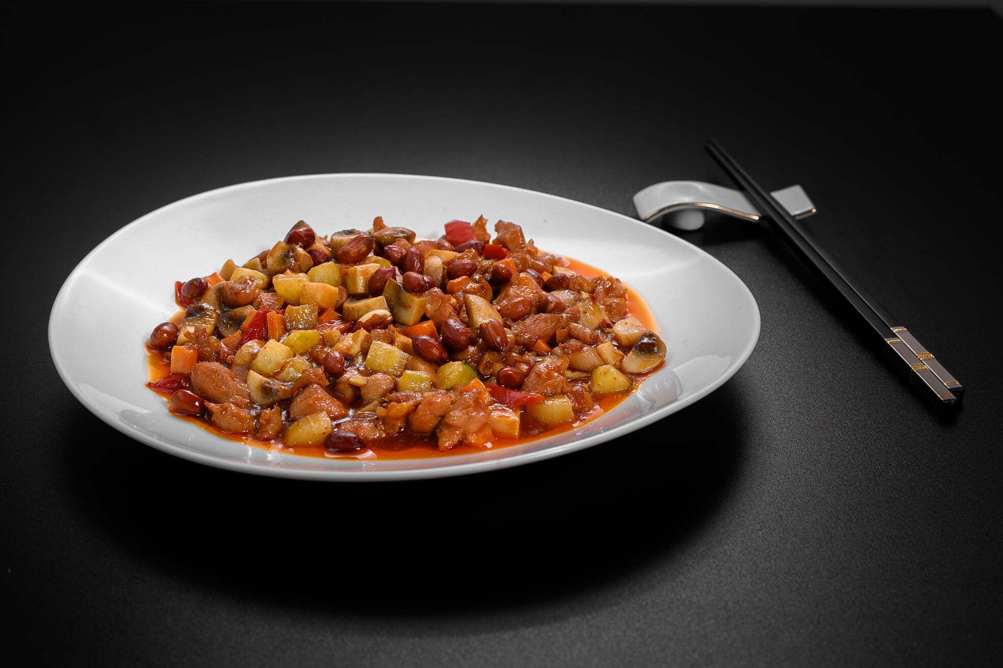 Un plato de guiso con frijoles y verduras sobre una superficie oscura.