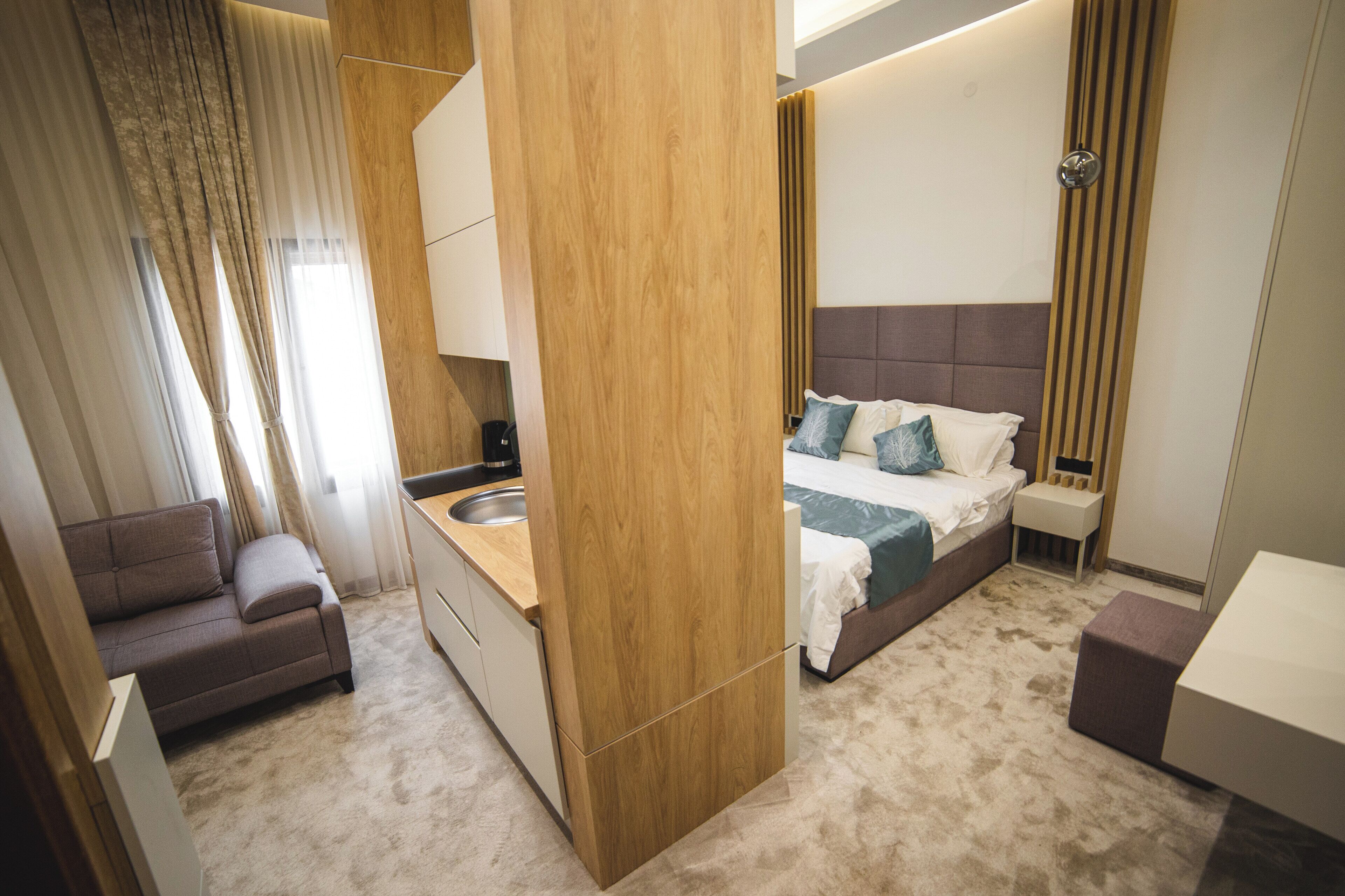 Un dormitorio moderno con cama, mesita de noche y un pequeño rincón de descanso.