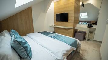 Een moderne slaapkamer met een bed, een wandtelevisie, een bureau met stoel en een klein raam.