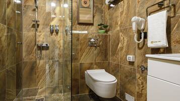 Ein Badezimmer mit Duschkabine, Toilette, Fön und Handtuchhalter.