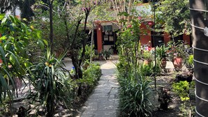 A garden pathway leading to a building with a brick facade and a red door. - Sunrise Cottage (Kathmandu)