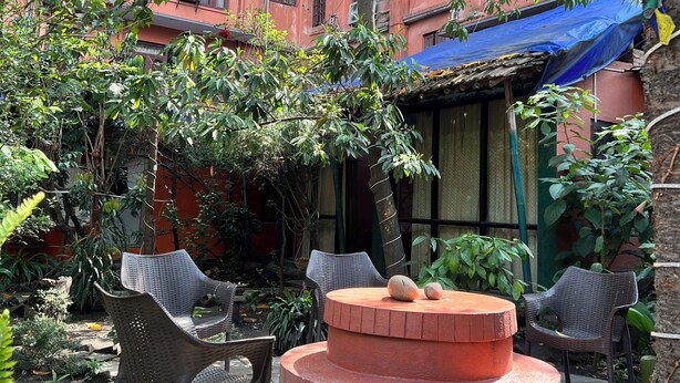 A courtyard with a circular seating area, surrounded by potted plants and trees. - Sunrise Cottage (Kathmandu)