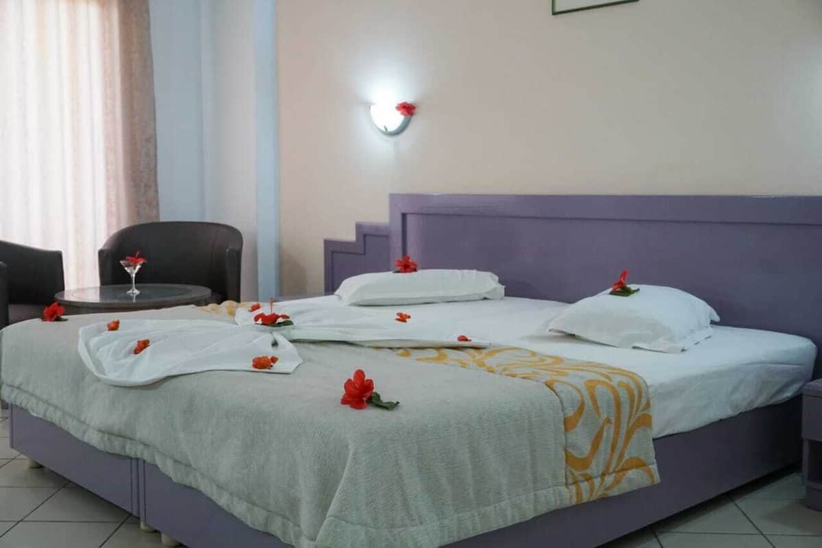 A hotel room with a bed, a chair, a small table, and a nightstand.