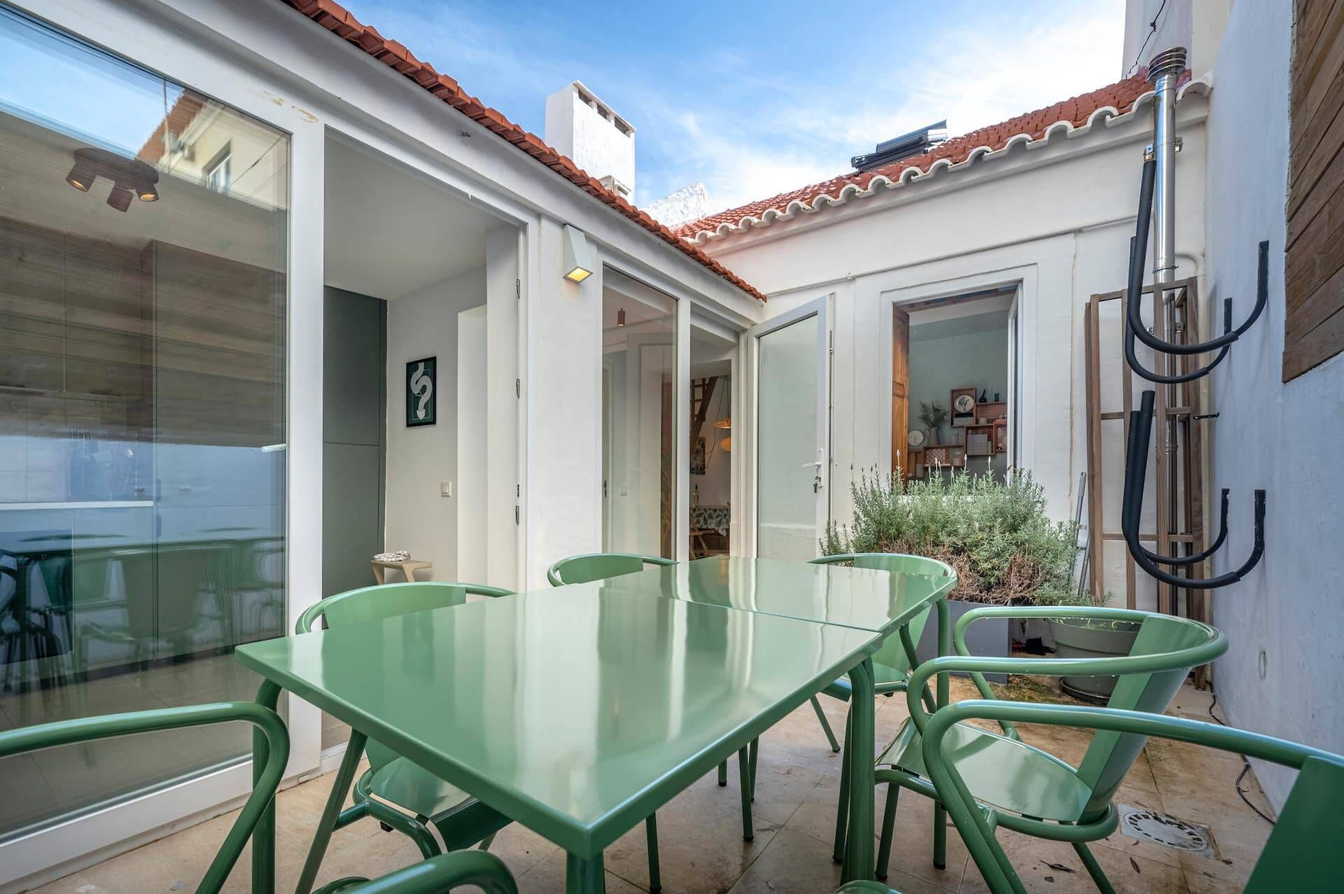 Une terrasse avec une table et des chaises en verre, un toit en tuiles et un espace jardin agrémenté de plantes.