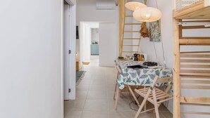 Spiseområde med et bord dækket til to personer, en træstige og en hængende lampe.