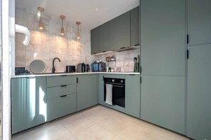 Una cocina moderna con armarios grises, horno empotrado e iluminación colgante.