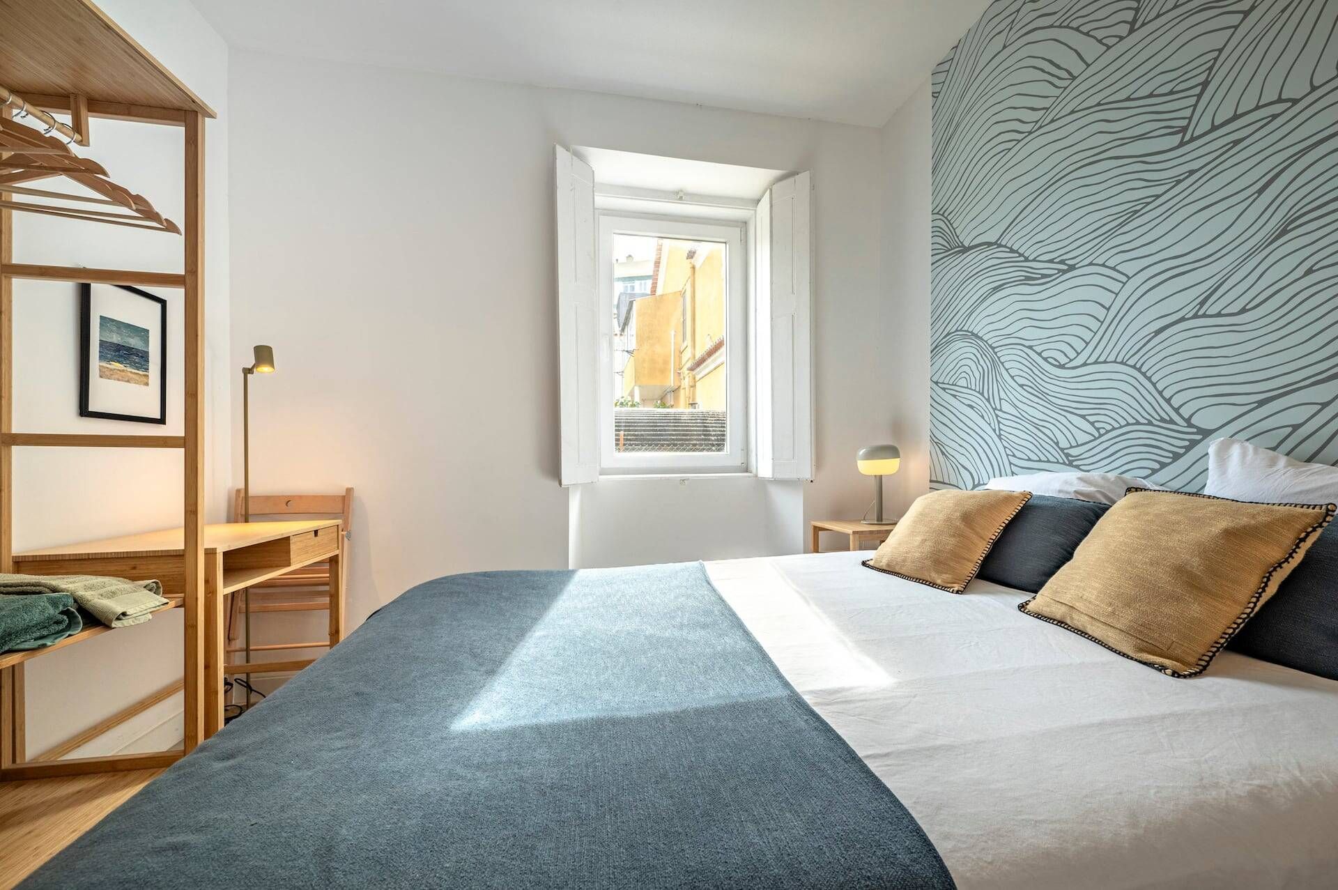 Ein Schlafzimmer mit Bett, Fenster, Schreibtisch und Kleiderschrank.