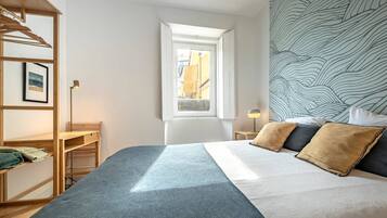 Ein Schlafzimmer mit Bett, Fenster, Schreibtisch und Kleiderschrank.