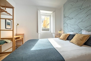 Un dormitorio con una cama, ventana, escritorio y armario.