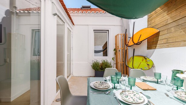 En spiseplads med et bord til fire, en potteplante og en gul paraply.
