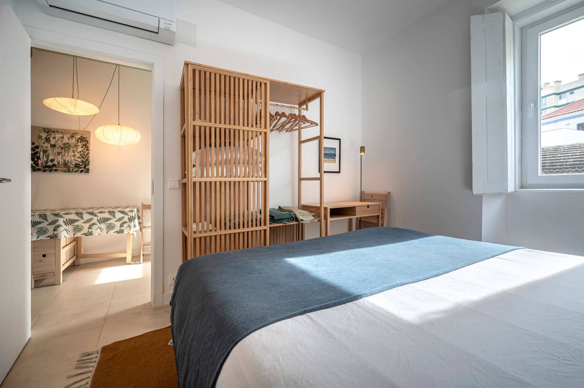 Une chambre à coucher comprenant un lit, une armoire en bois, un bureau et un luminaire suspendu.