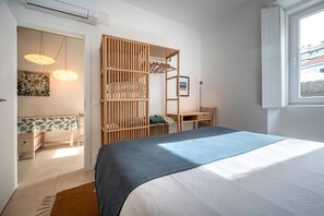 Un dormitorio con una cama, un armario de madera, un escritorio y una lámpara colgante.