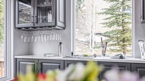 Une cuisine avec une fenêtre donnant sur l’extérieur, un meuble à vin et un vase rempli de fleurs.