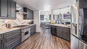 Une cuisine moderne avec des meubles de couleur sombre, des appareils électroménagers en acier inoxydable et un dosseret en marbre.