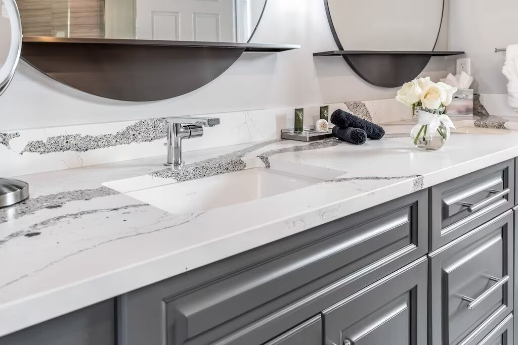 A modern bathroom with a white marble countertop, a double sink, and a large mirror.