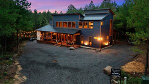 A two-story lodge with a covered patio and a gravel driveway. - Sip and Stay Hideaway (Broken Bow)