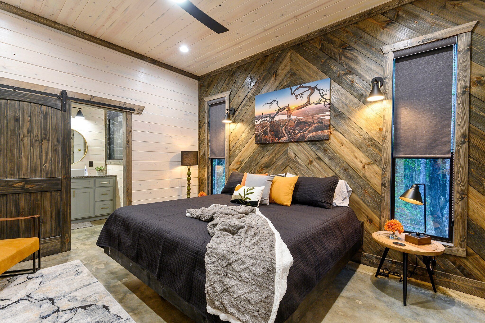 Un dormitorio con una cama grande, paredes de madera y un cuadro de un paisaje.