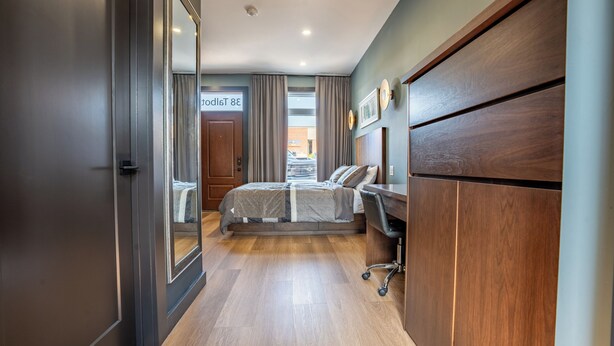 Quarto de hotel moderno com cama, escrivaninha e guarda-roupa.