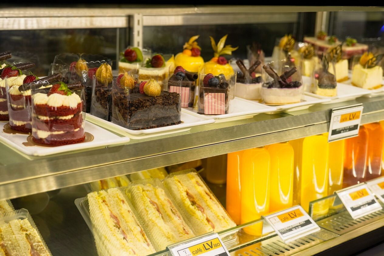 Una variedad de postres expuestos en una vitrina, incluyendo pasteles en capas y postres con frutas.