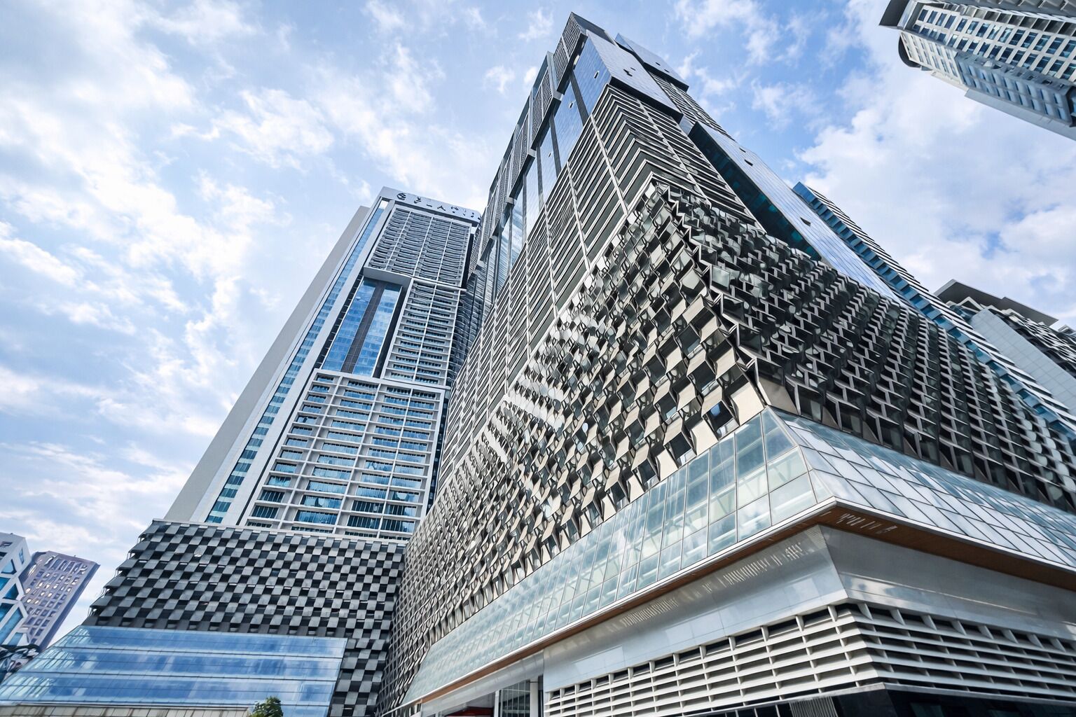 A modern high-rise building with a distinctive geometric facade, multiple glass windows, and a prominent vertical design element.
