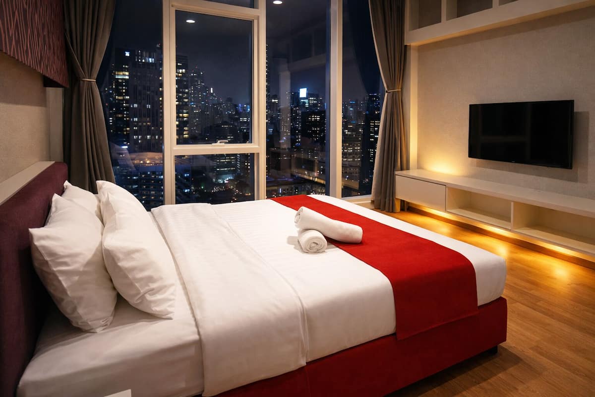 A hotel room with a large bed, a TV, and a city view.