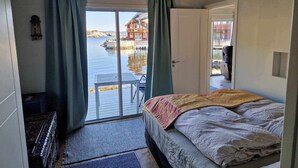 A bedroom with a bed, a view of a dock and water, and a door leading to a balcony. - Cottage 2 meters from the sea, 2 hours from Bergen in Norway. Unike location (Vestland)