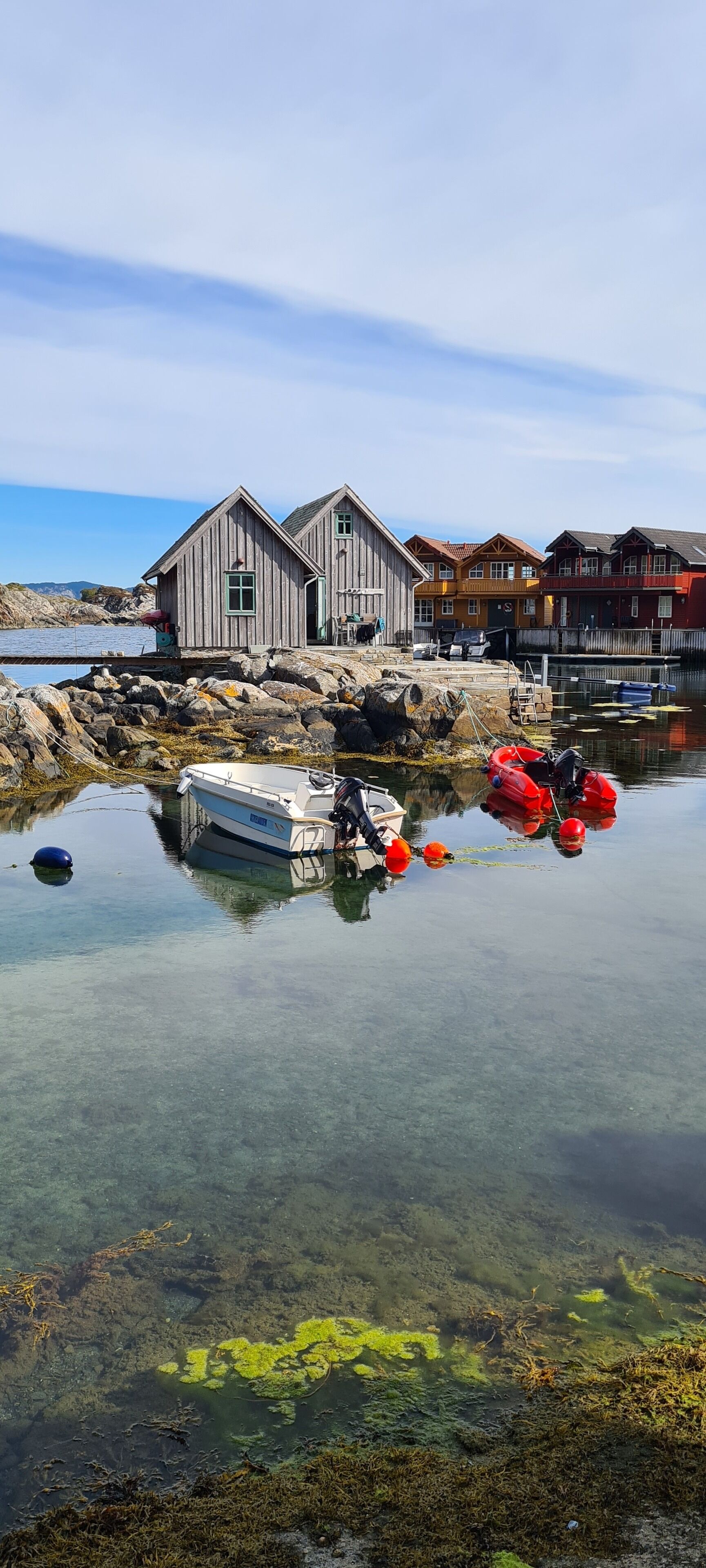Un bâtiment situé au bord de l’eau, doté d’un quai, de bateaux et d’une eau claire dans laquelle se reflète la structure.